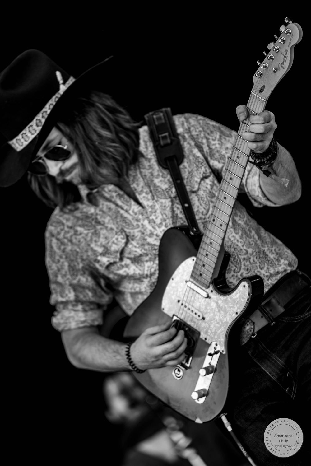 Black and white photo of a guitarist in a cowboy hat and sunglasses playing a Fender Telecaster on stage.