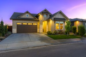 Craftsman-style home exterior at dusk with warm lighting, stone accents, and a two-car garage.