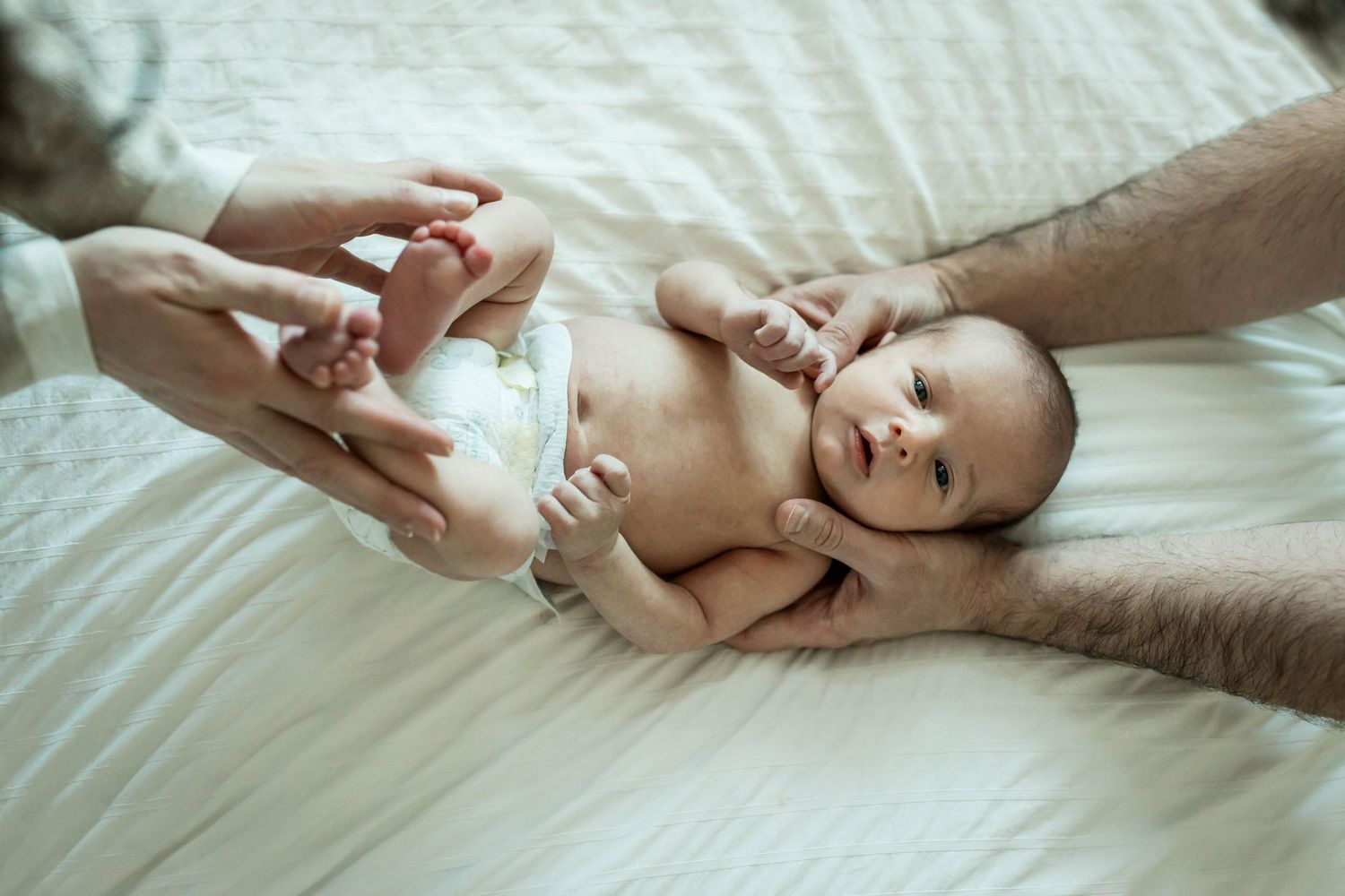 Newborn baby held in parents' hands during lifestyle newborn photography session at home in Calgary
