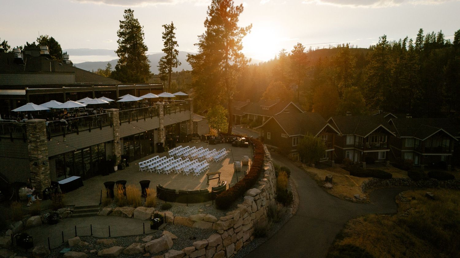 Aerial sunset view of a predator ridge resort with outdoor patio event space surrounded by pine trees.