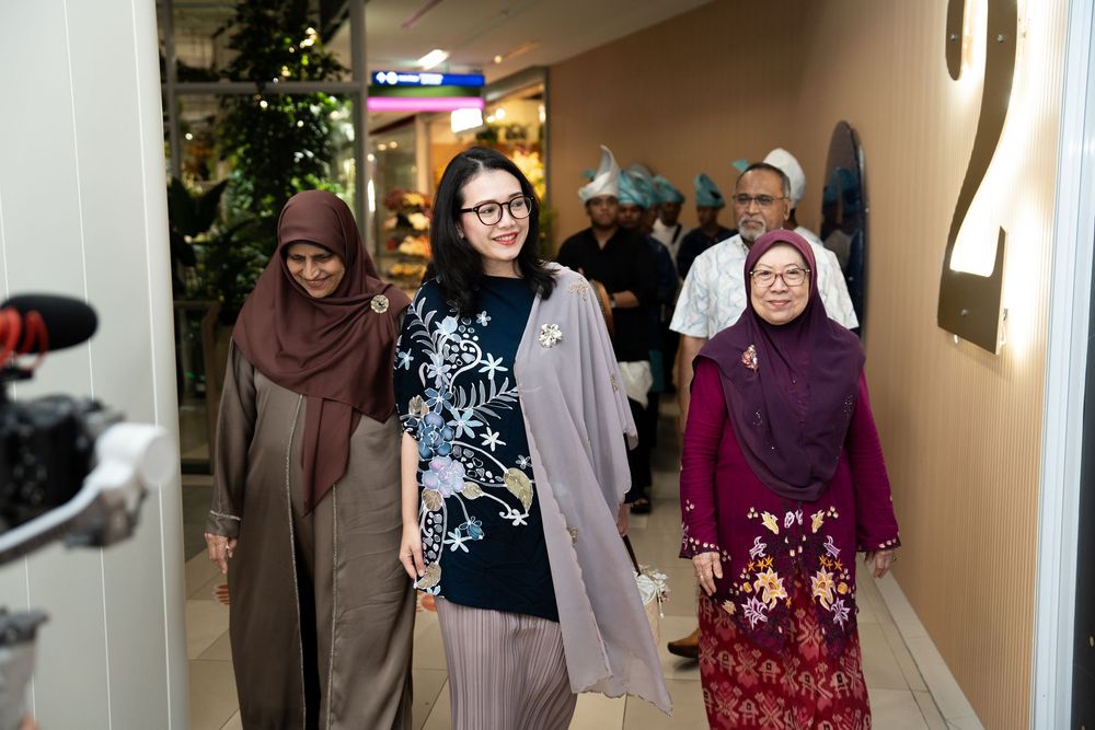 Three women walking together in a modern indoor venue, wearing elegant traditional and contemporary outfits.