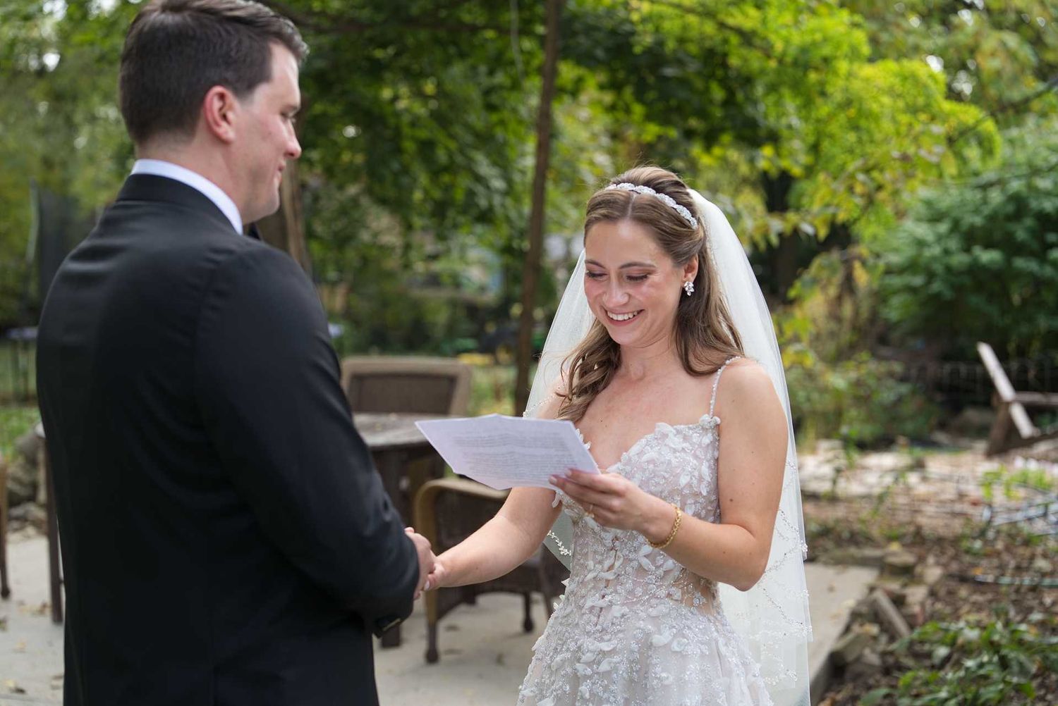 Bride in lace gown and veil reads wedding vows to groom outside The Westin Great Southern Columbus Wedding Venue