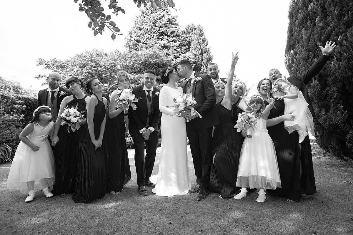 Black and white wedding party photo with bride, groom, bridesmaids, and groomsmen posing outdoors at Skitby House wedding venue
