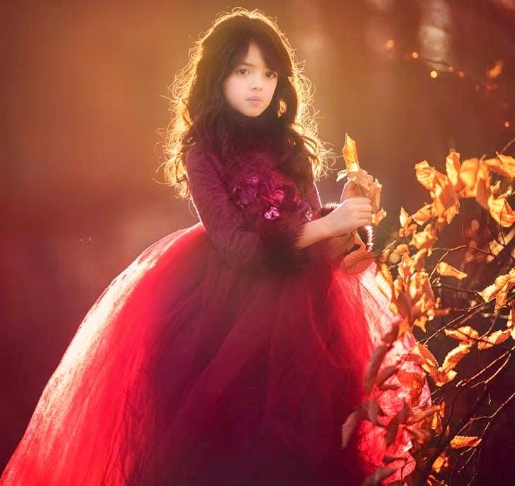 Close-up portrait of a young girl in a burgundy dress surrounded by warm autumn colors in South Jersey.