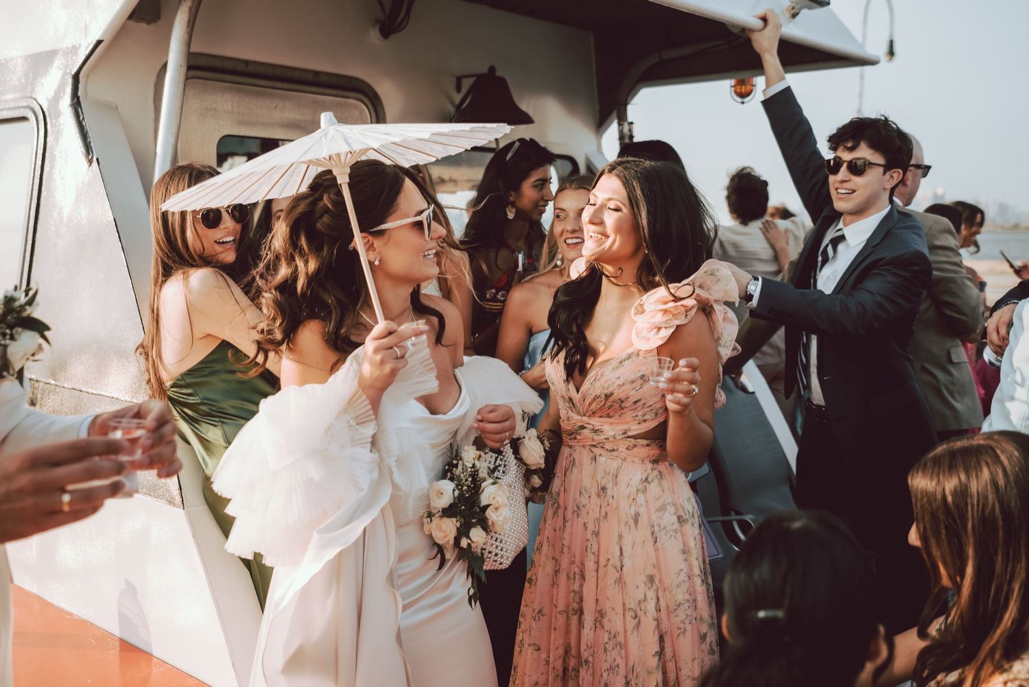 Bride and bridesmaids laughing and celebrating near a vintage white van at an outdoor wedding reception.