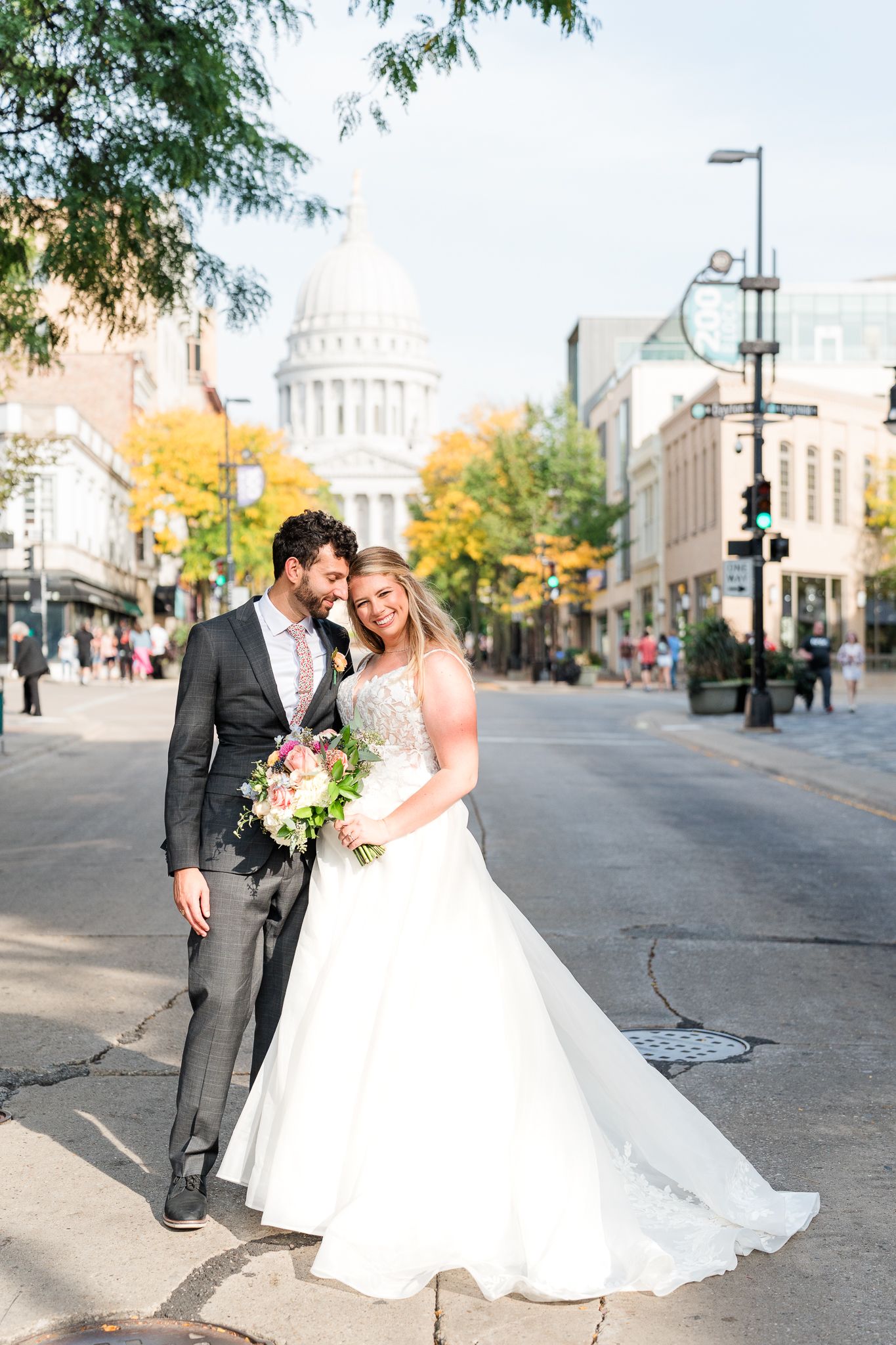 Wedding couple posing on city street with historic capitol building in background.