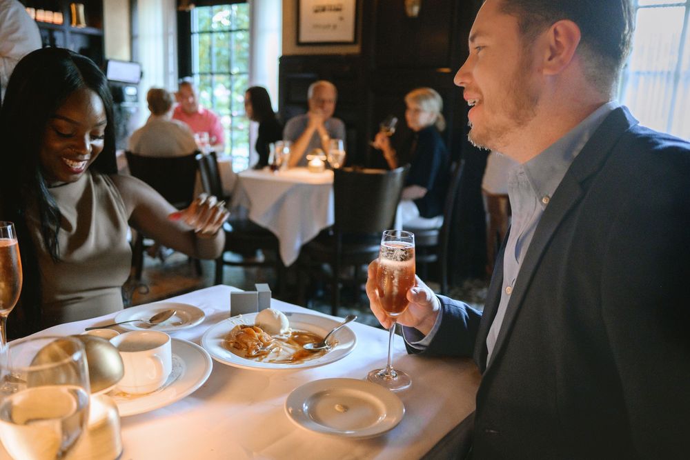 Couple enjoying drinks and appetizers at an upscale restaurant during a lively lunch gathering.