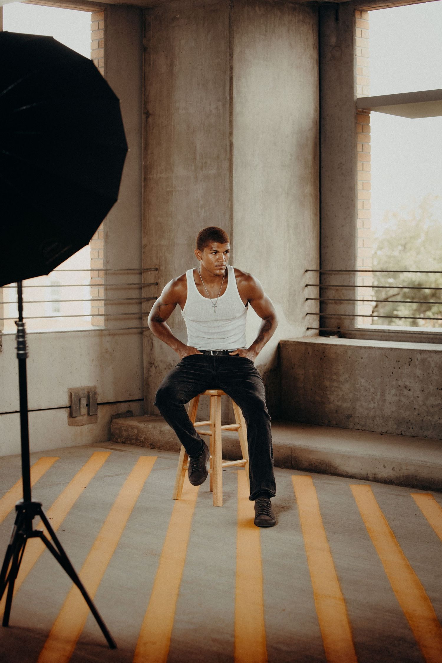 Editorial portrait of a man seated in an industrial setting with studio lighting