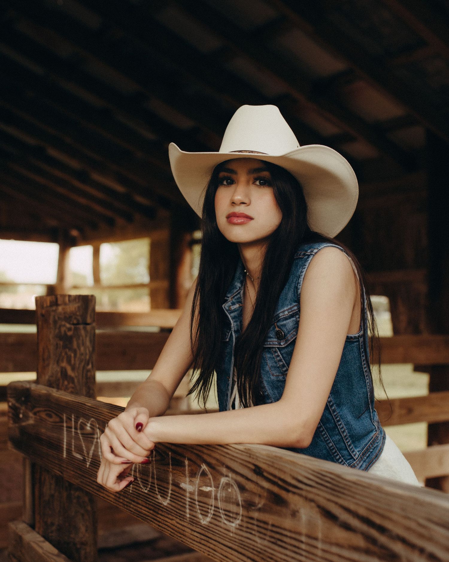 Western editorial portrait of a woman wearing a cowboy hat in a rustic setting