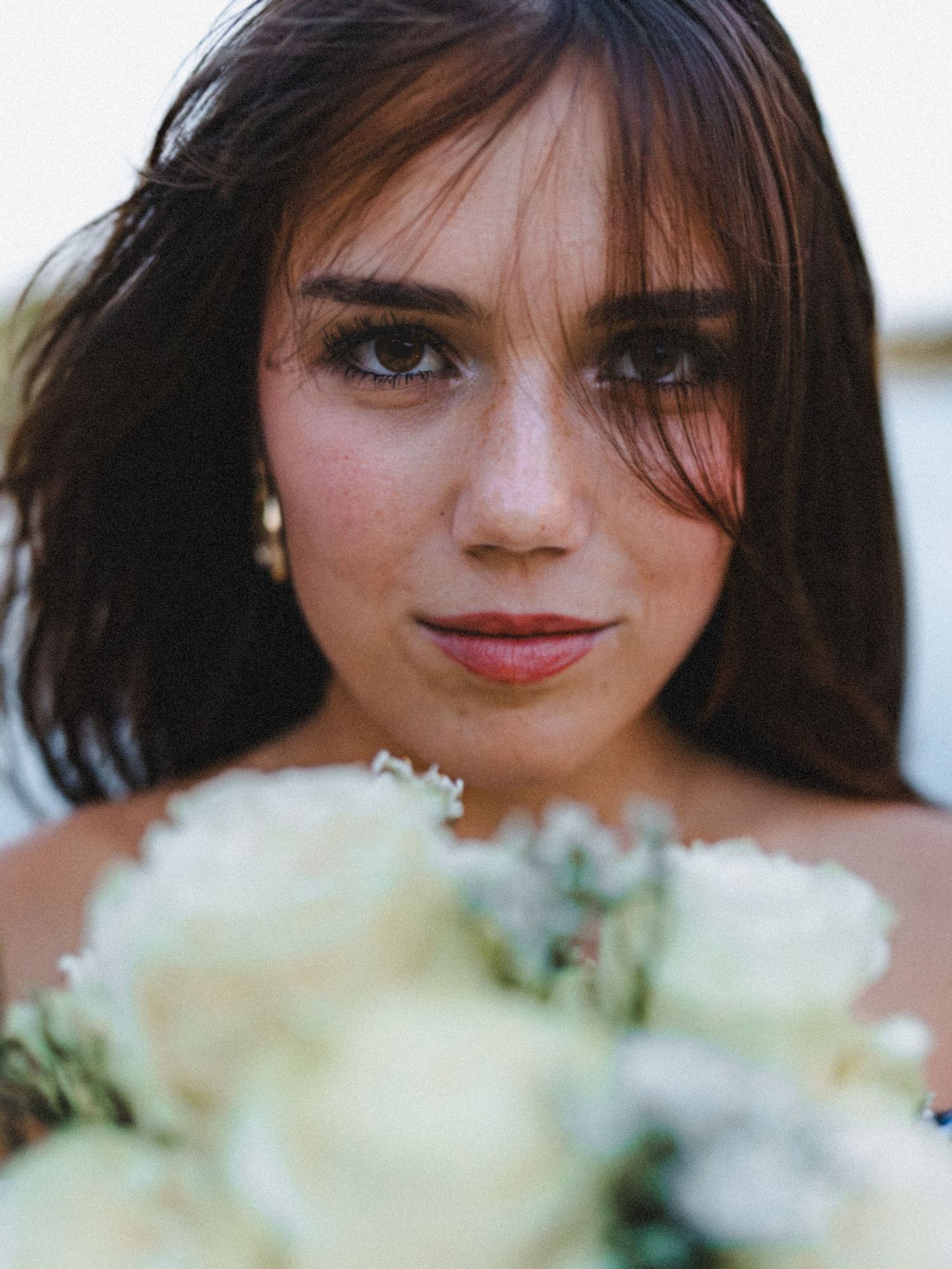 Close-up editorial portrait of a woman holding white flowers