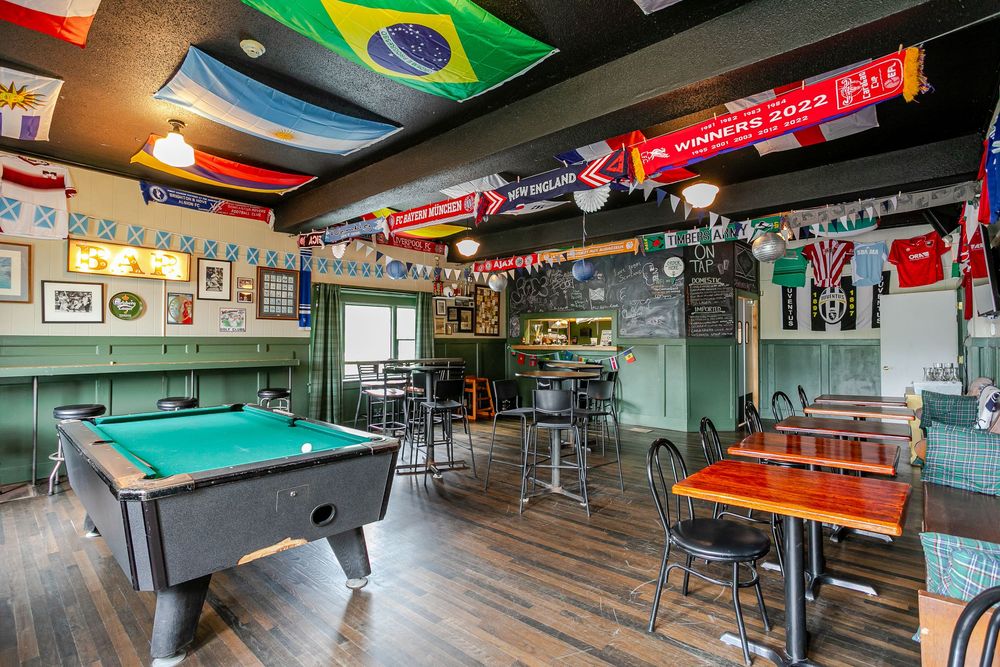 Lively sports bar interior with pool table, international flags on ceiling, and chalkboard walls.