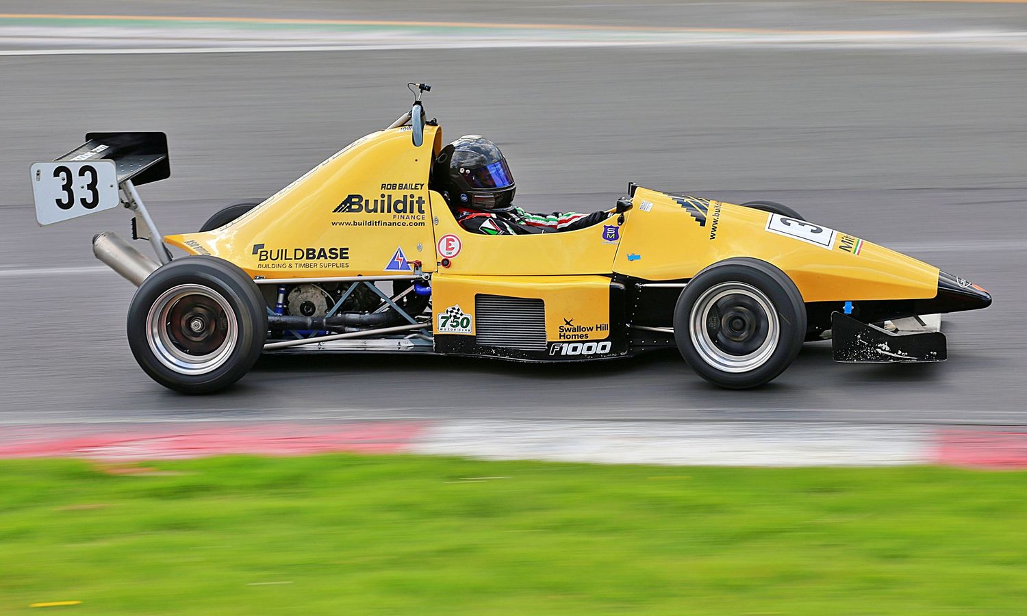 Yellow number 33 Buildit Formula Ford single-seater racing car speeding along a motorsport circuit.