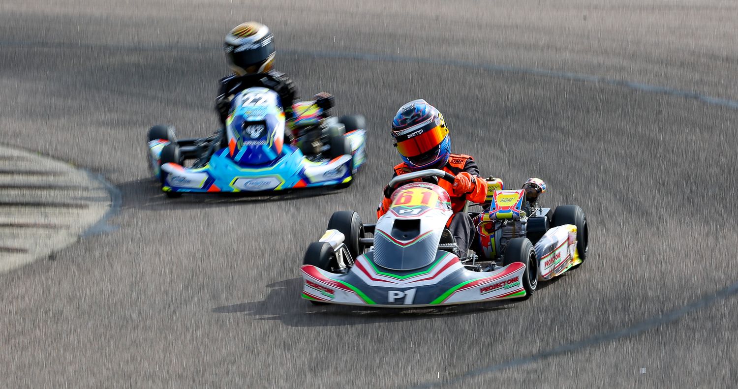 Two go-karts racing on a circuit, number P1 leading in close competitive race.