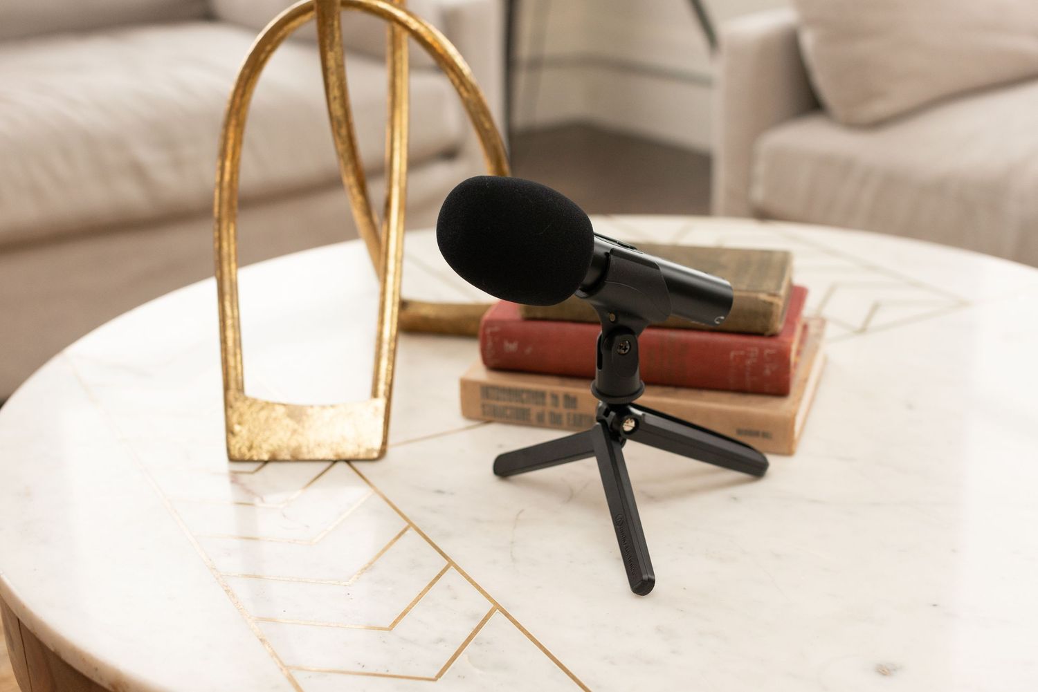 podcast mic sitting on a modern table with books and sculpture