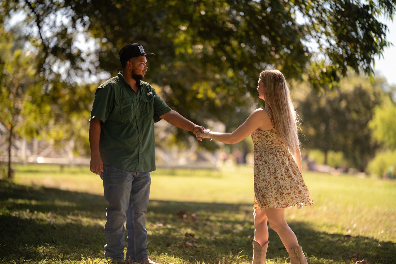 Young couple holding hands and dancing playfully in a sunny green park in Salado Texas