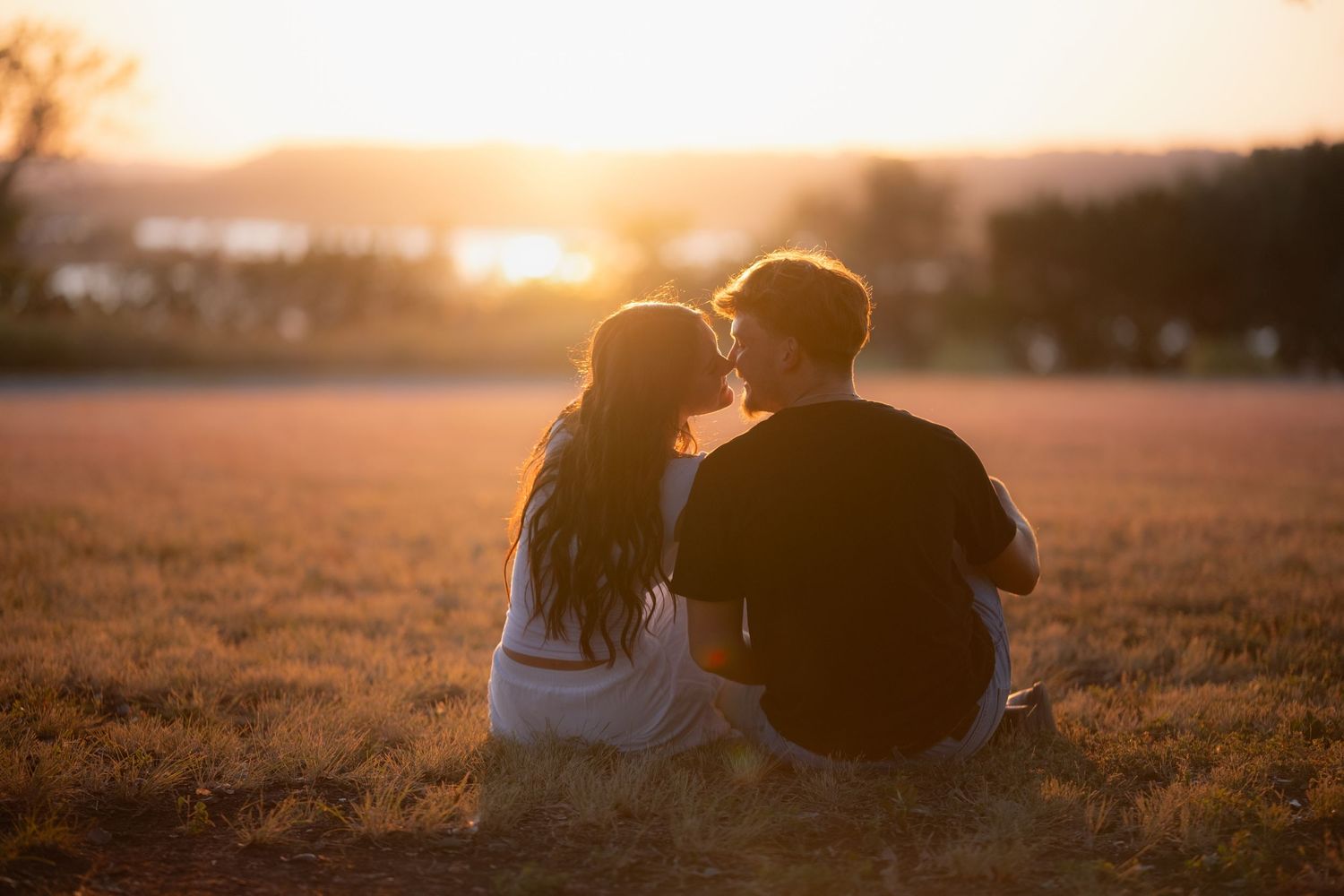 Couple sitting together in a golden field watching a romantic sunset in Belton Texas