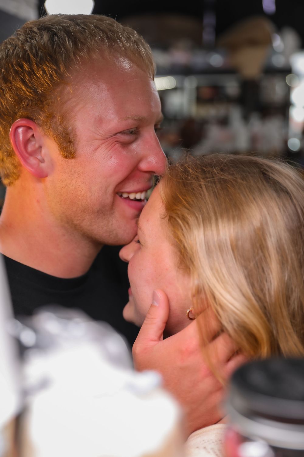 Happy couple sharing an intimate moment, man tenderly holding womans face while smiling.