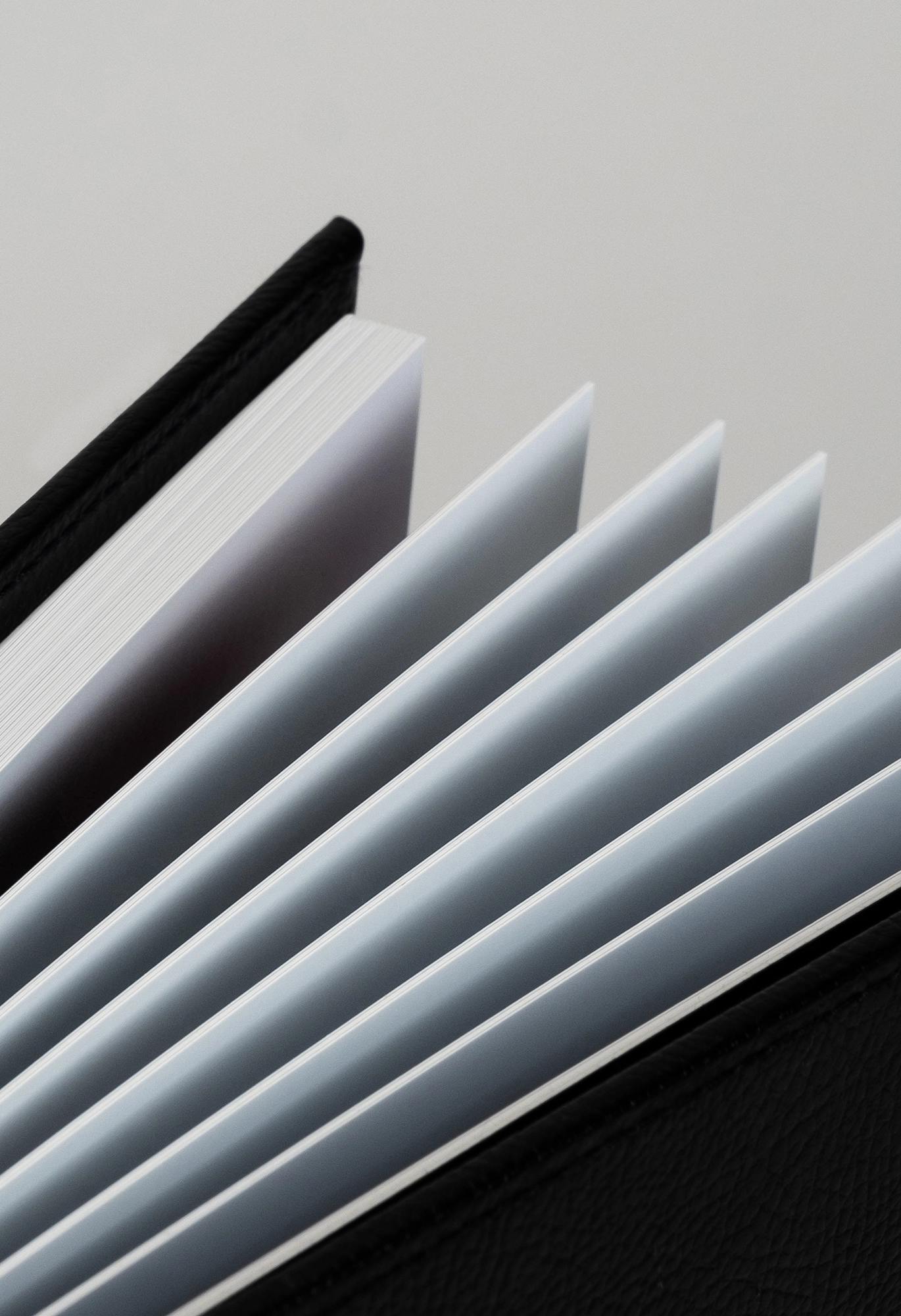 Fanned pages of a black-bound photo album showing crisp white paper layers.