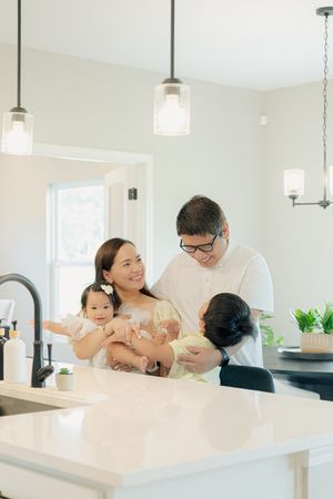 Happy family with two young children sharing a joyful moment together in a bright modern kitchen.