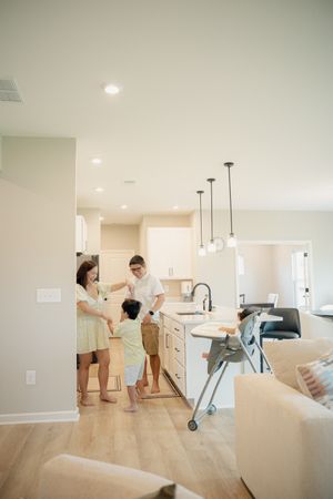 Family gathered in a bright, modern open-concept kitchen with pendant lights and hardwood floors.