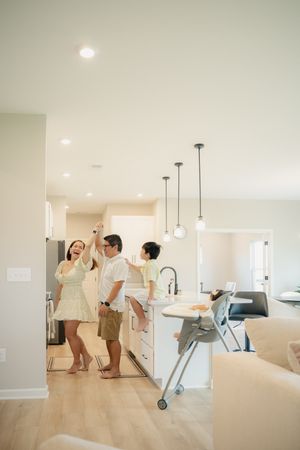 Family of three enjoying their modern open-concept kitchen with pendant lights and hardwood floors in a bright new home.
