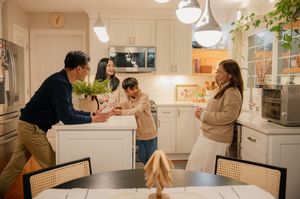 Family gathering in a bright kitchen, sharing fresh groceries and warm conversation around a dining table.