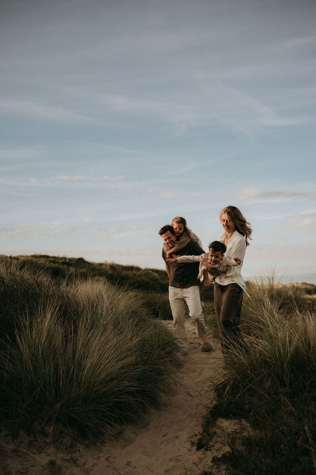 Een familie in de duinen, wandelen en spelen met elkaar met een fotoshoot tijdens goldenhour, dichtbij Eindhoven.