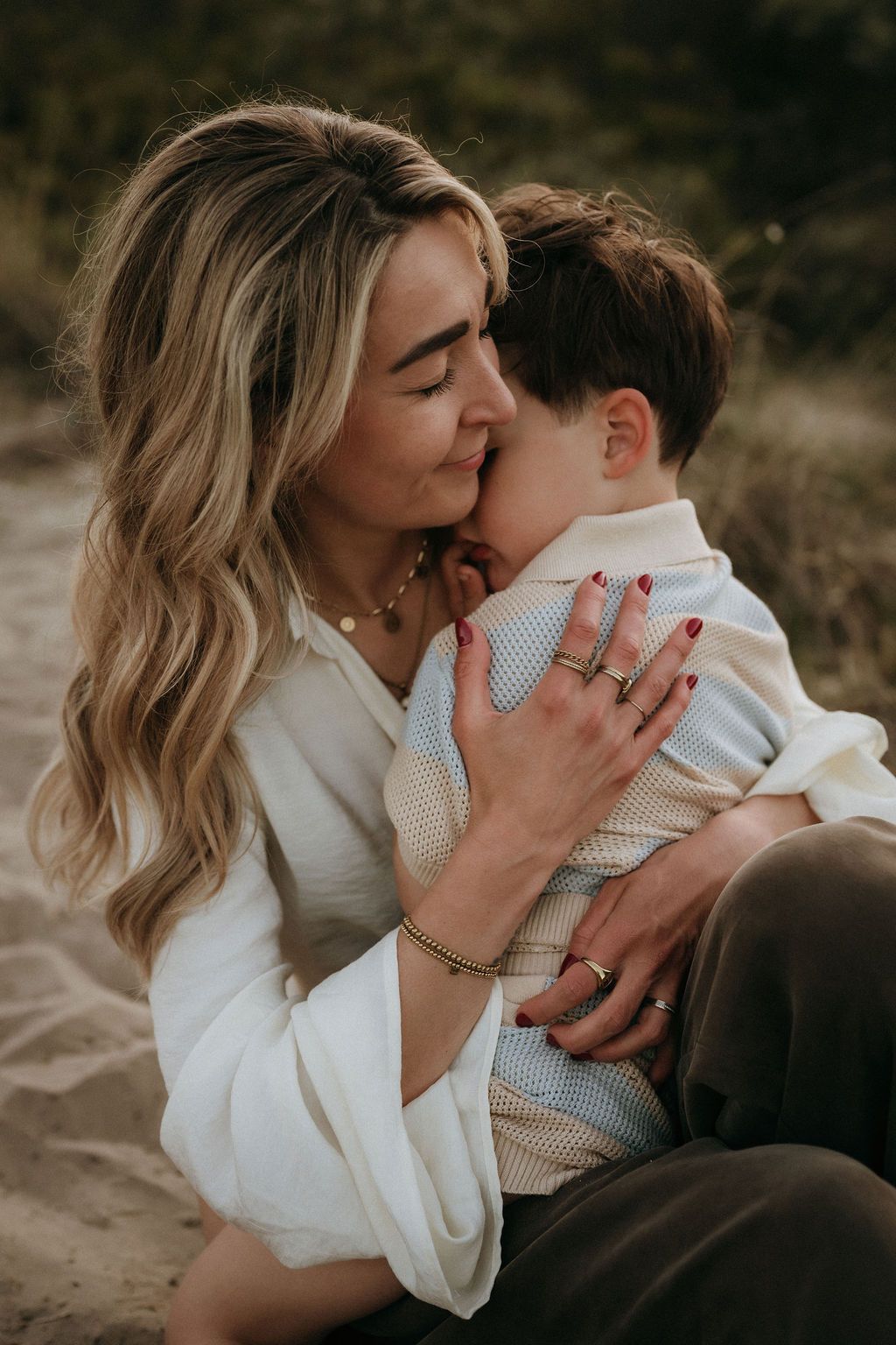 Een moeder die haar zoon intiem knuffelt tijdens een fotoshoot aan zee, bij de duinen, Geldrop dichtbij Eindhoven.