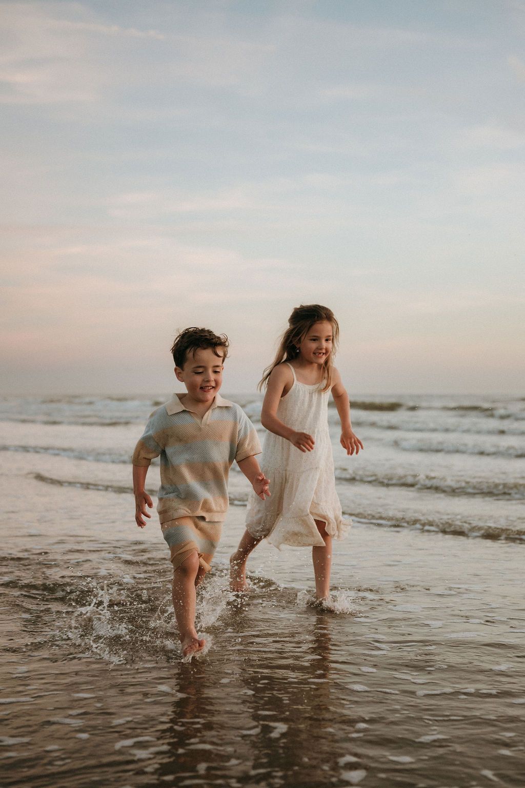 Twee blije kinderen zijn hier aan het rennen, tijdens een fotoshoot met goldenhour aan zee, dichtbij Eindhoven.