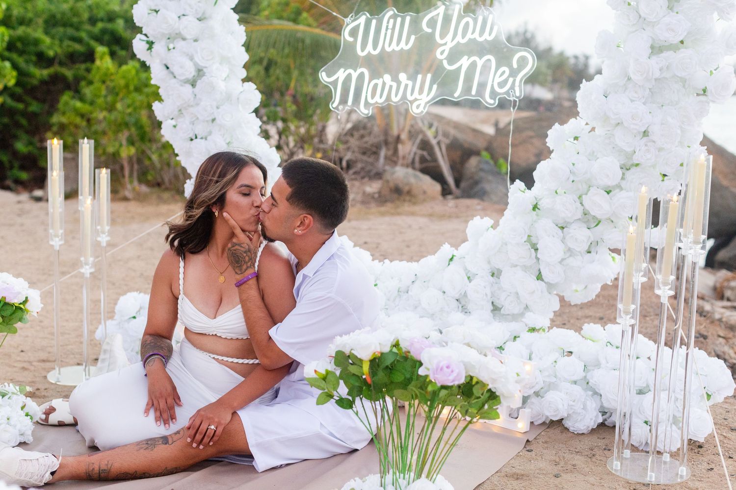 Marriage proposal. Man, woman, and decorative setup with white flower heart overlooking the ocean in Río Grande, Puerto Rico.