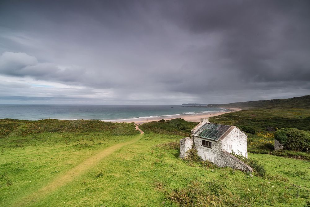 Tipico cottage irlandese vicino alla spiaggia sotto un cielo nuvoloso