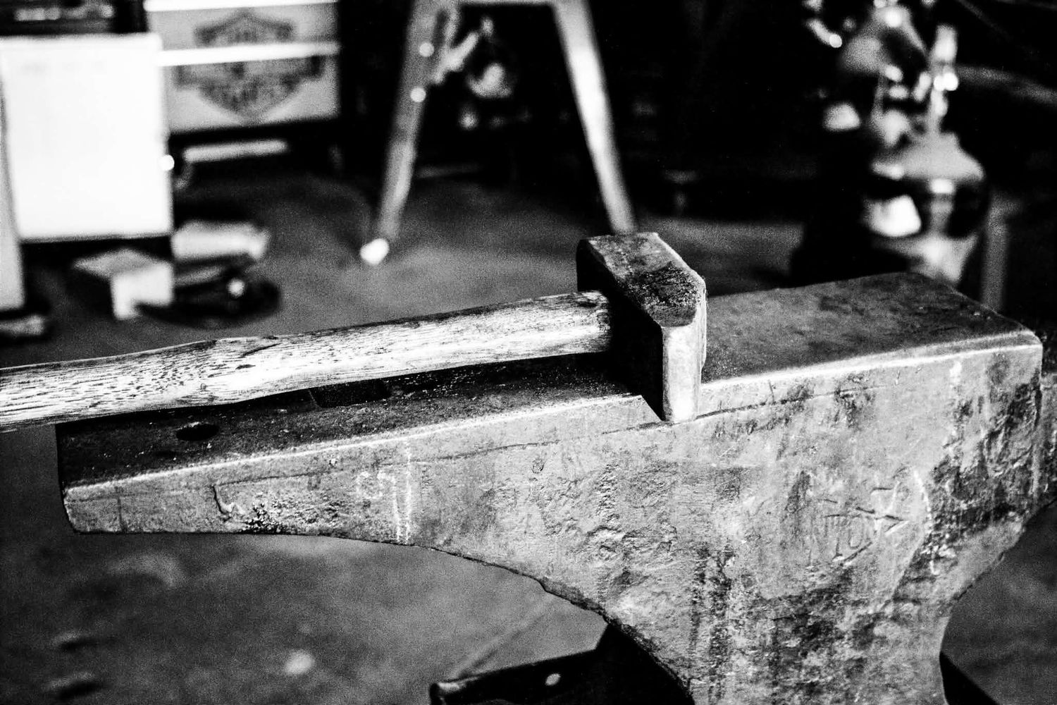 Black and white photo of a vintage metal anvil in a workshop, used for blacksmithing and metalworking.