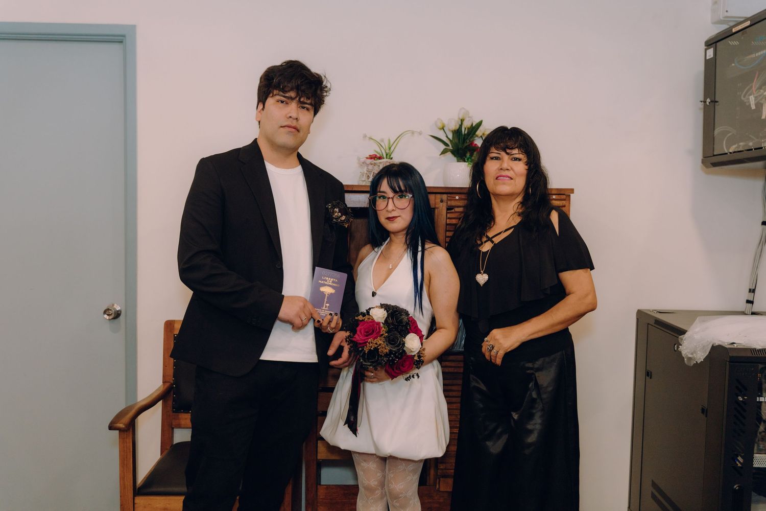 Bride and groom pose with older female guest at intimate small wedding celebration.