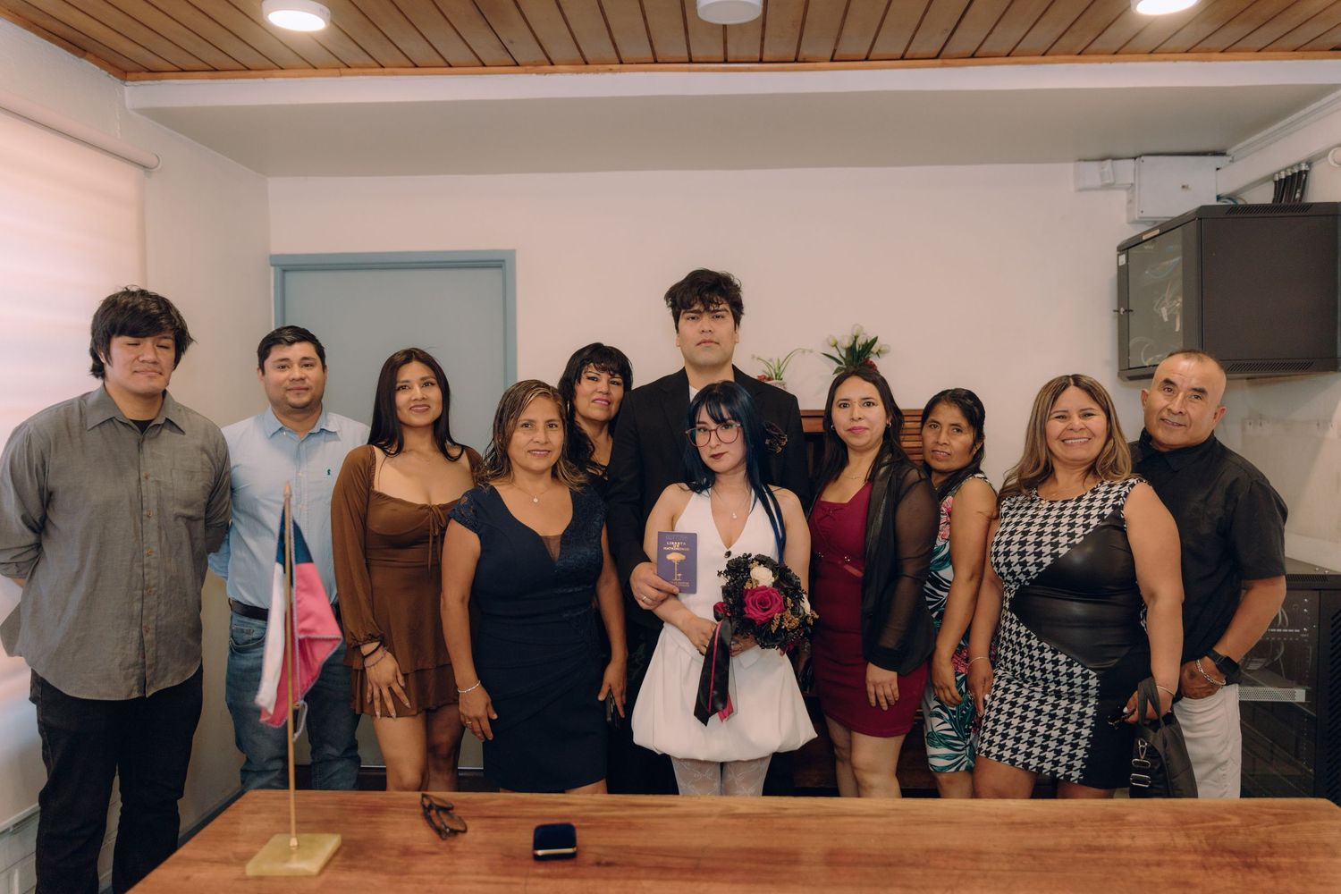 Large group of family and friends pose together indoors at a civil wedding ceremony celebration.