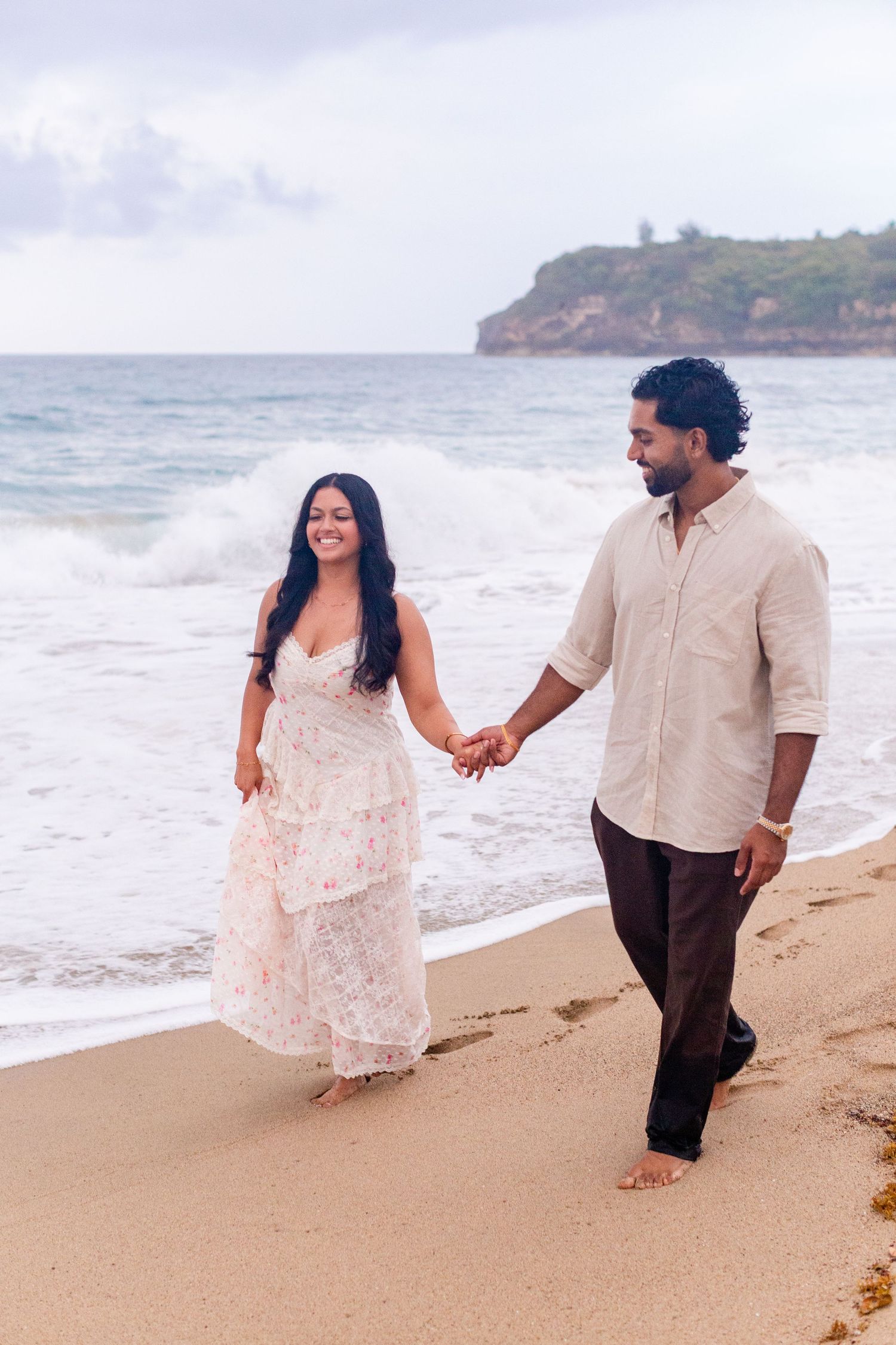 Engagement portrait on the beach. Man and woman walking at the water's edge. Playa Guajataca, Isabela, Puerto Rico.
