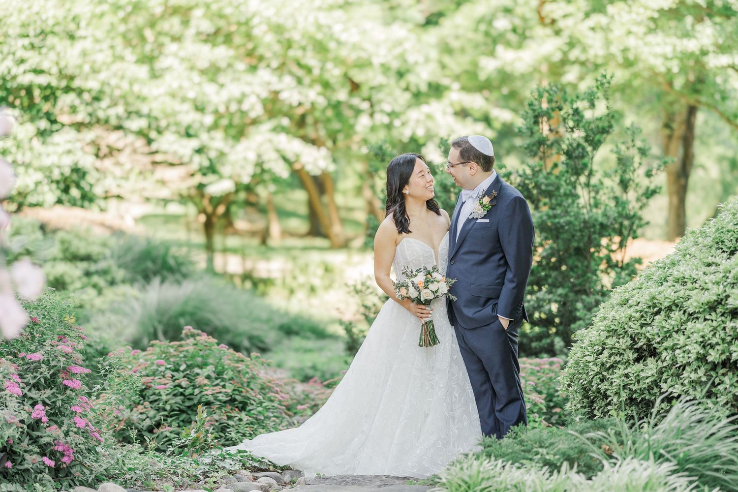 Bride and groom share a romantic moment surrounded by lush blooming gardens on their wedding day.