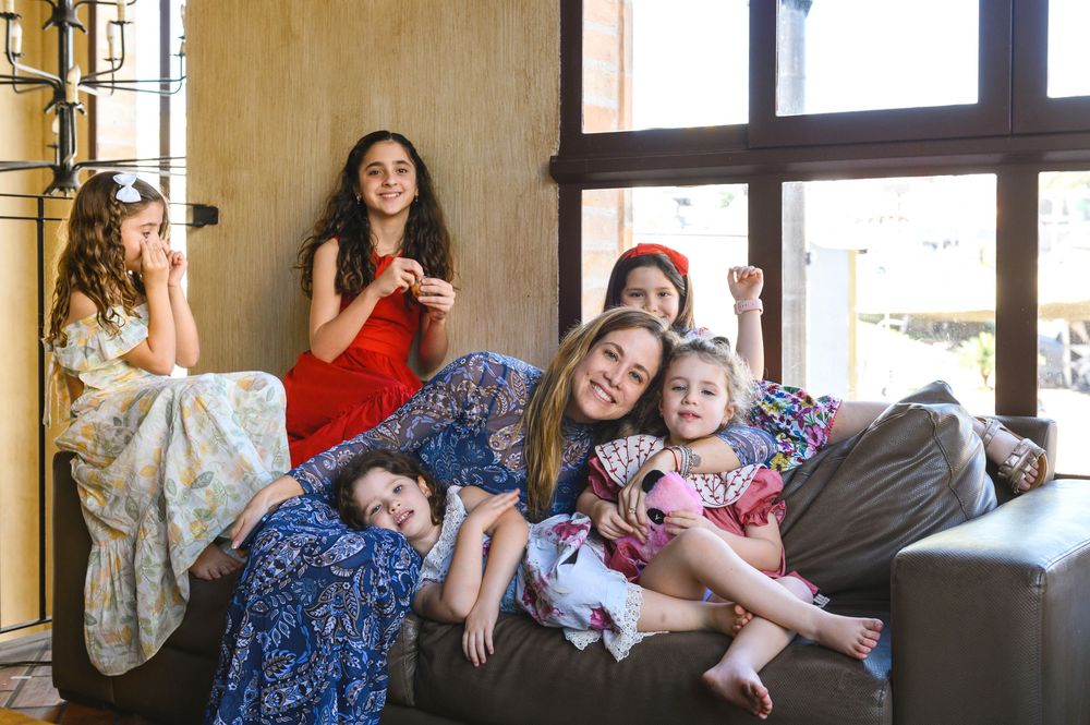 Group of women and girls smiling and relaxing together on a couch in a bright, cozy living room.