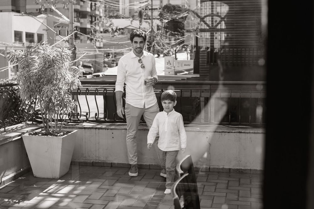 A man and young child stand together on an outdoor terrace in a black and white photo.
