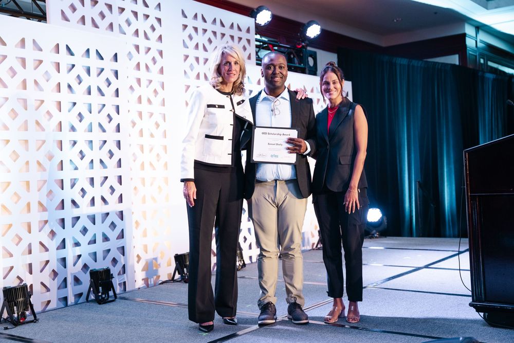 Three people pose on stage at The Westin Long Beach while presenting a certificate award at a formal event.