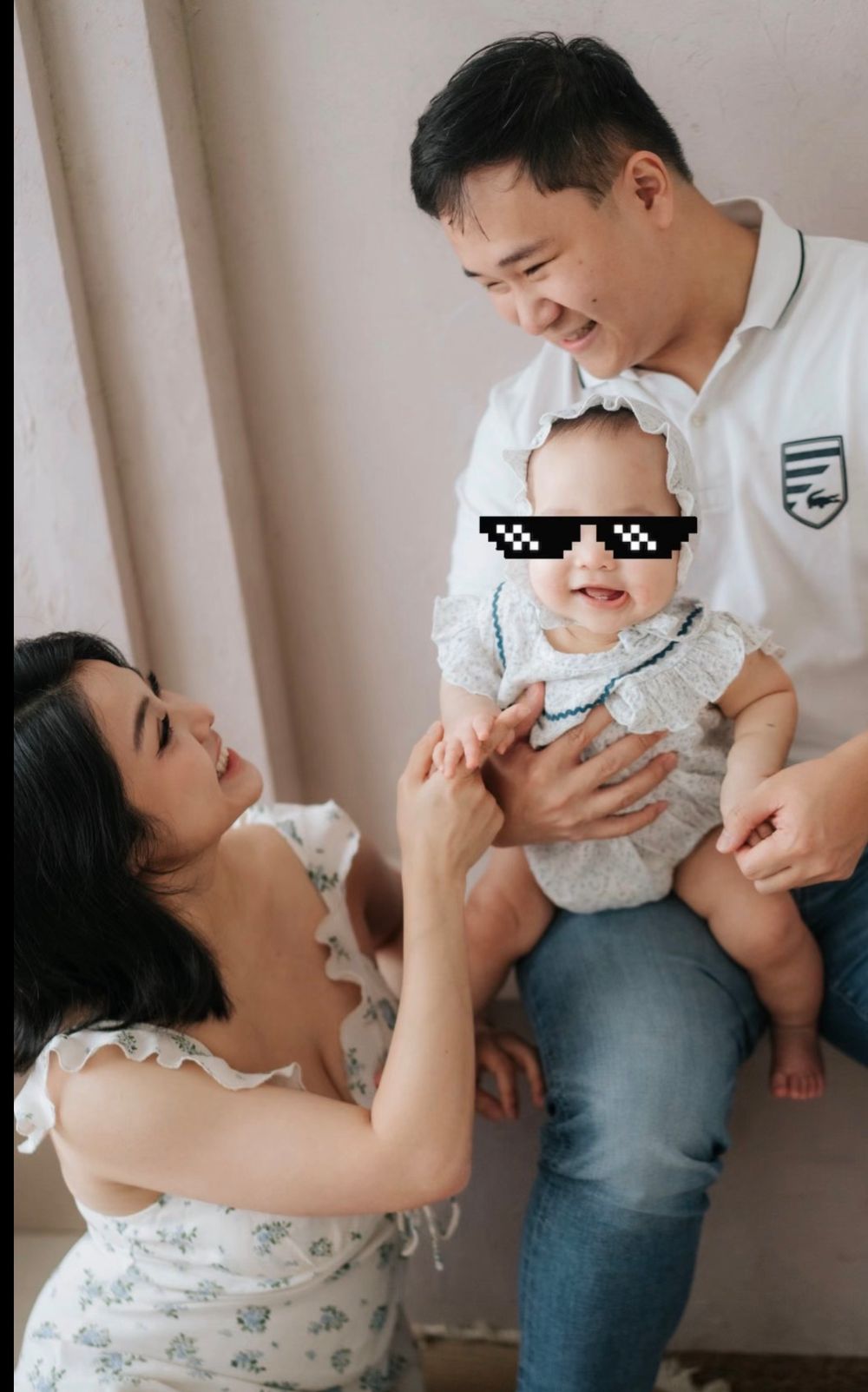 Happy Asian family portrait with parents and baby wearing novelty pixel sunglasses sticker, smiling together indoors.