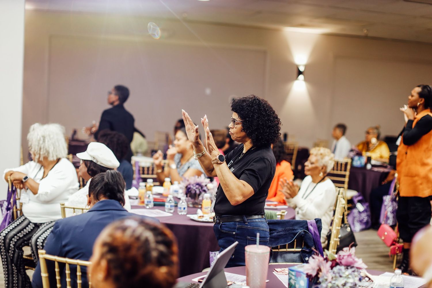 Diverse group of women networking at an elegant banquet event with purple table settings and gold chairs.