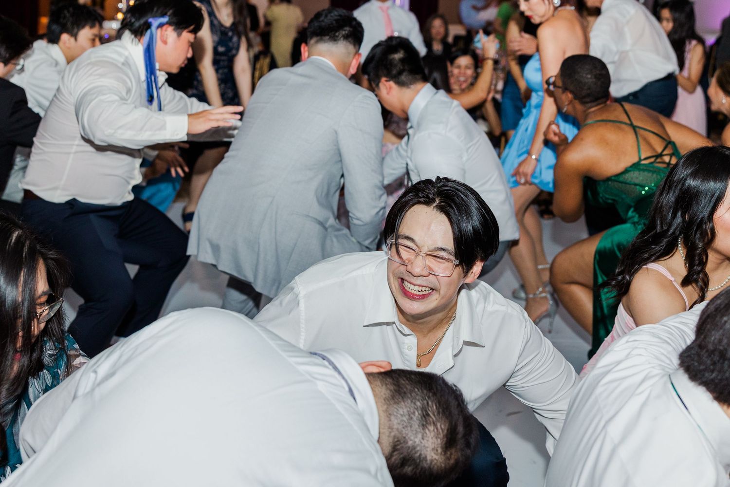 Guests laughing and dancing on the floor at a lively wedding reception party.