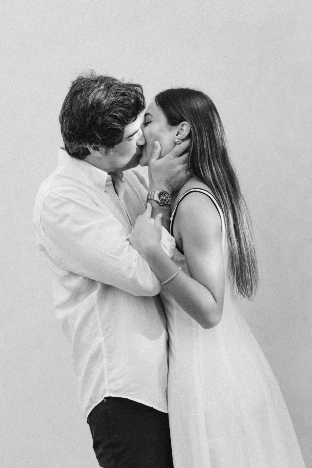 Black and white photo of a couple sharing a romantic kiss, man holding woman's face gently.