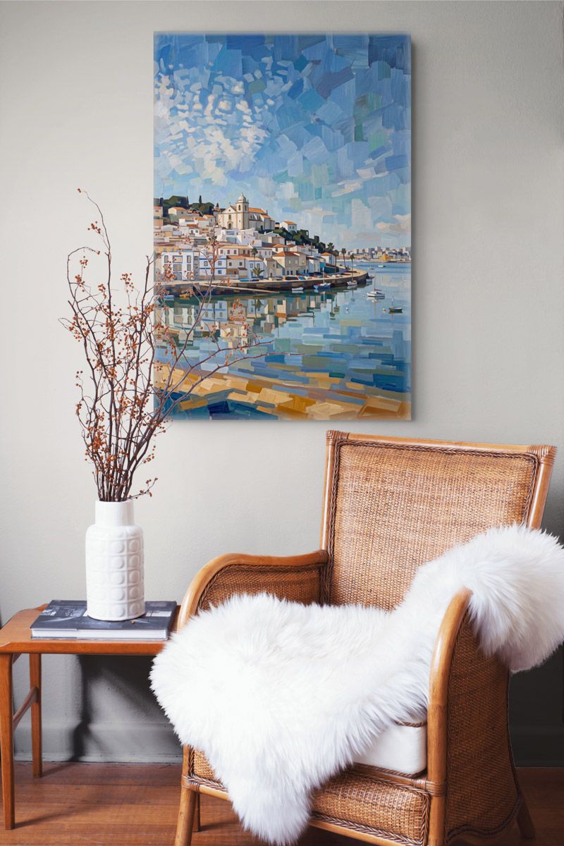 Mosaic-style coastal painting of a Mediterranean town reflected in calm blue waters, displayed above a rattan chair.