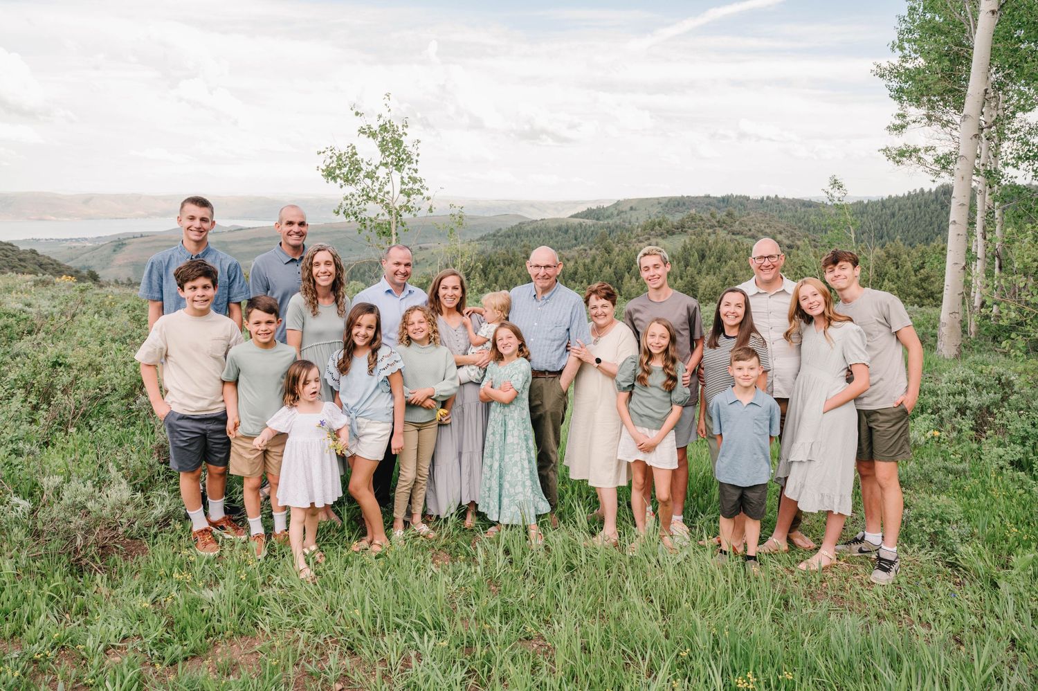 Large family group photo outdoors with mountains and trees in the background.
