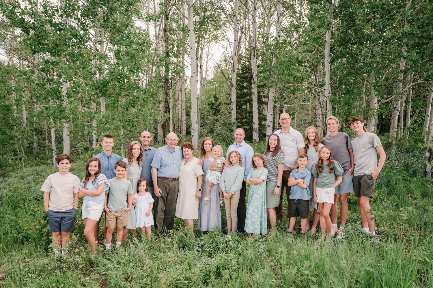 Extended family gathering poses for a group photo in a beautiful wooded mountain setting.