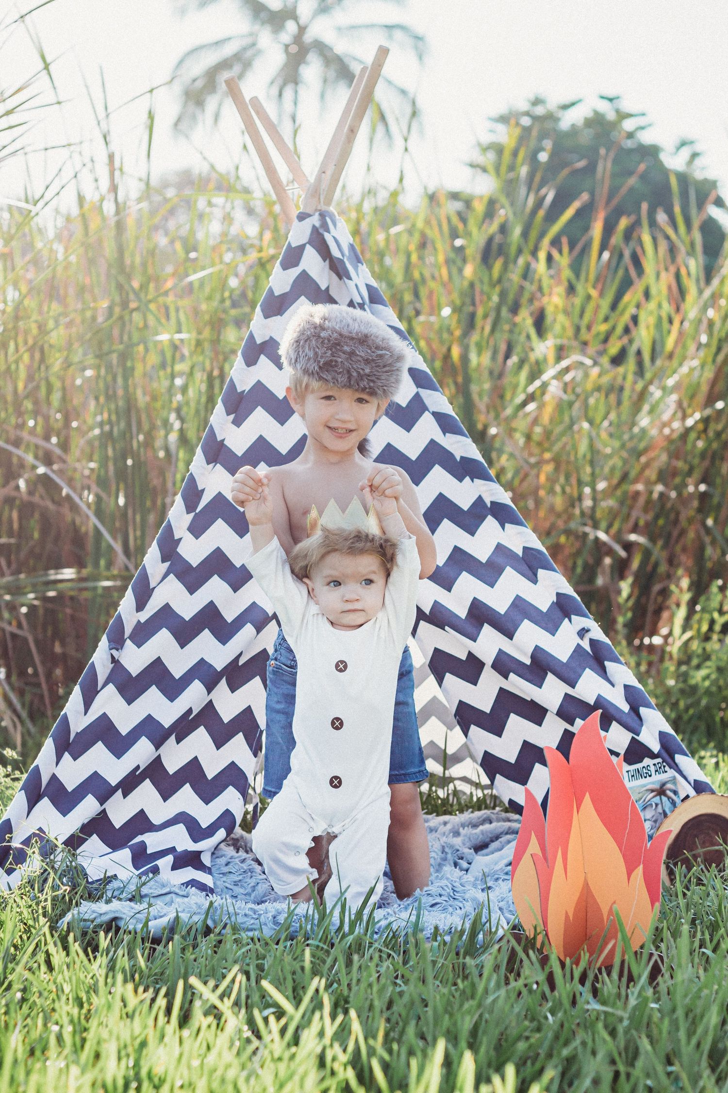 Three sequential photos of outdoor camping scene with navy chevron teepee tent and decorative paper campfire on grass.