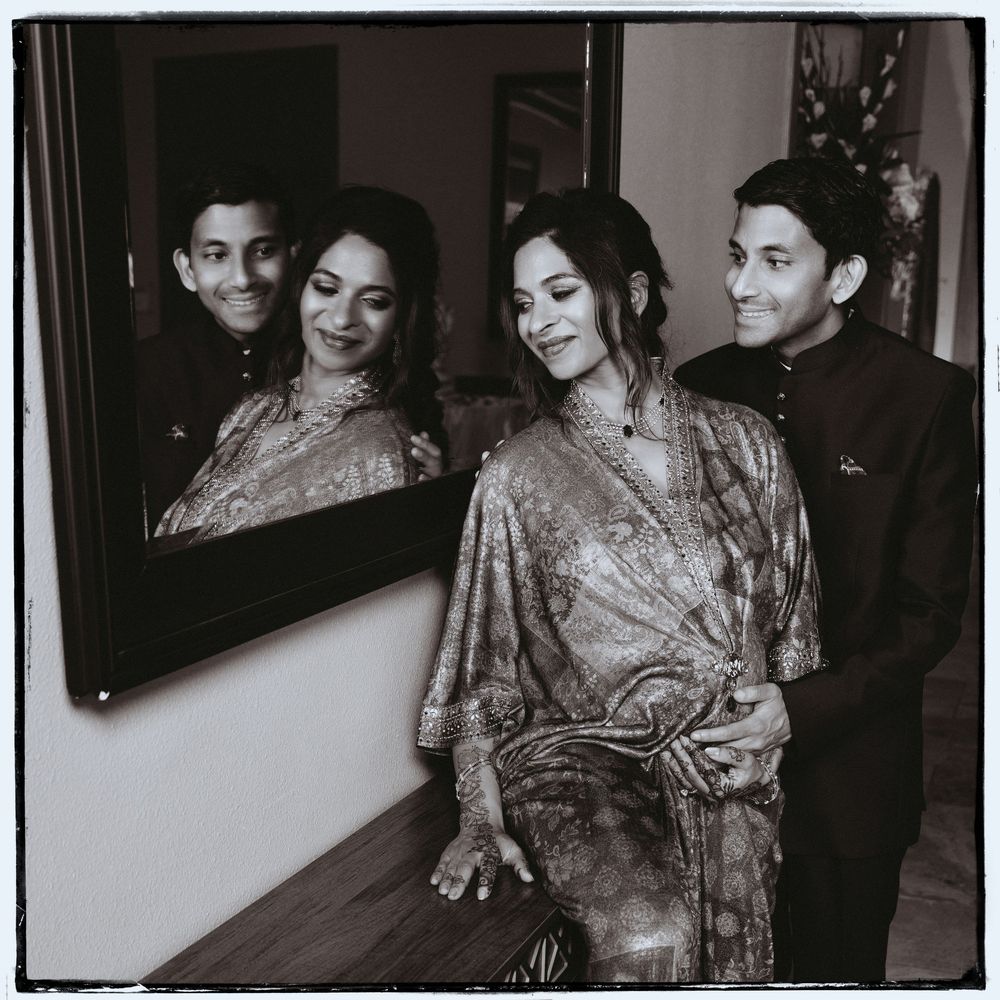 Couple posing elegantly in black and white photo beside a mirror reflecting their image at a Baby Shower event.