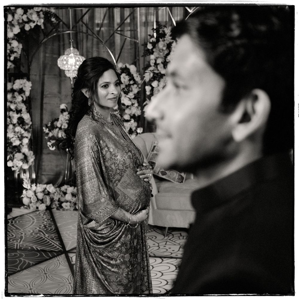 Black and white photo of an elegant couple at a floral decorated Indian wedding ceremony.