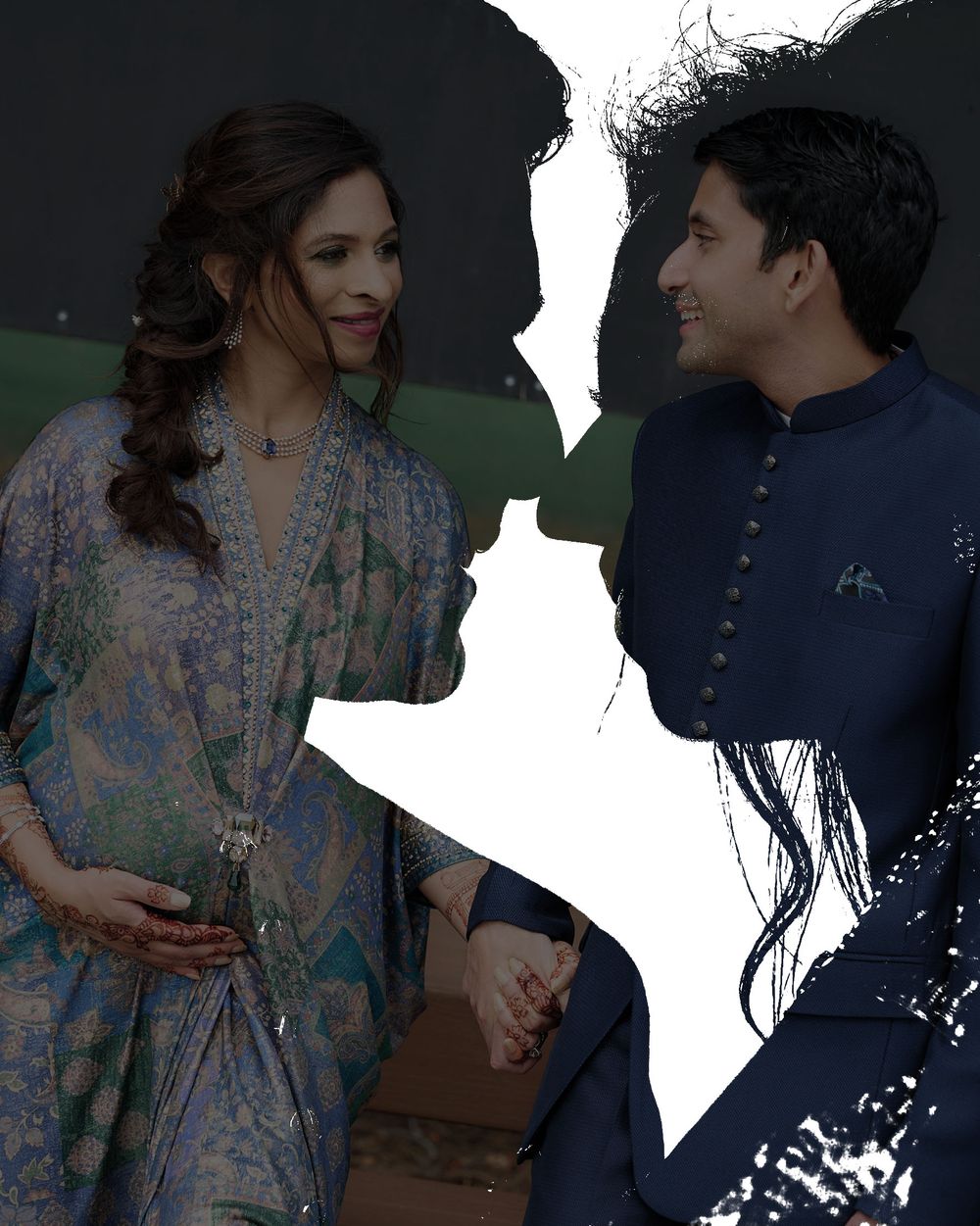A pregnant woman in blue floral dress holds hands with a man in navy kurta, with couple silhouettes in background.